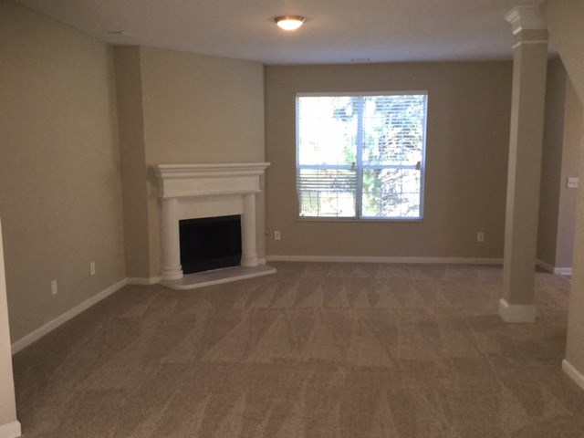 a empty living room with a fireplace and a window