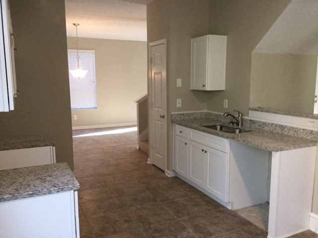 an empty kitchen with white cabinets and a sink
