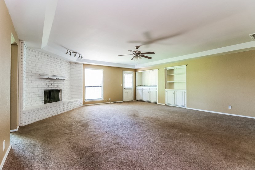 an empty living room with a ceiling fan