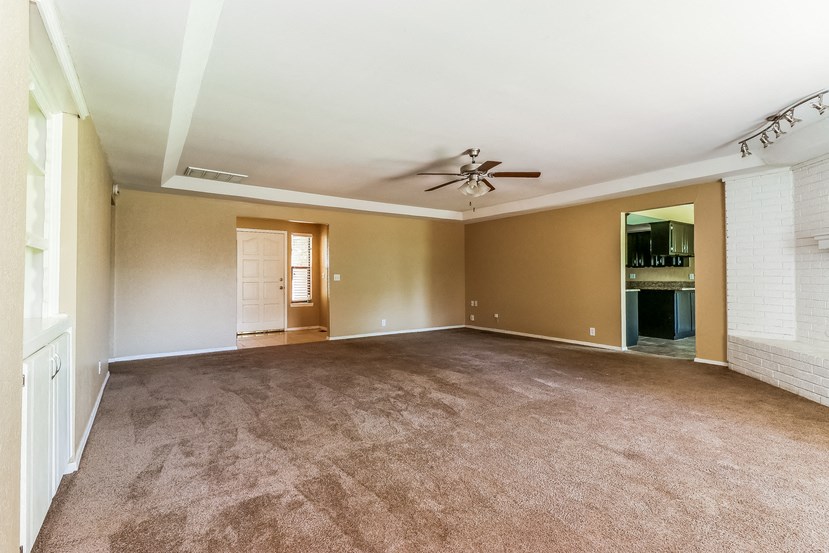an empty living room with a ceiling fan