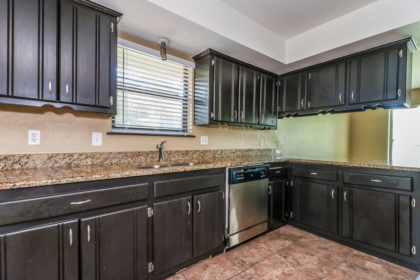 a kitchen with black cabinets and granite counter tops and a sink