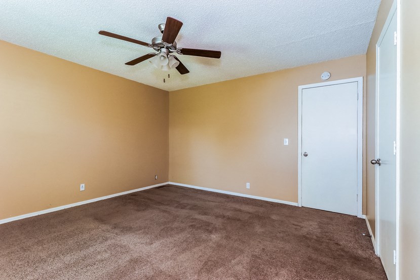 an empty living room with carpet and a ceiling fan