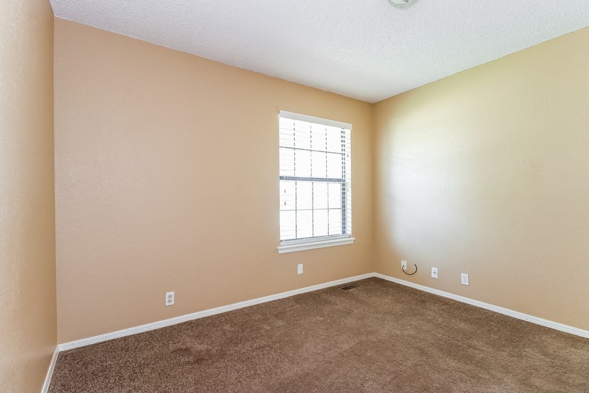 an empty living room with carpet and a window