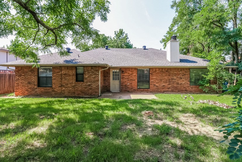 a brick house with a lawn and trees