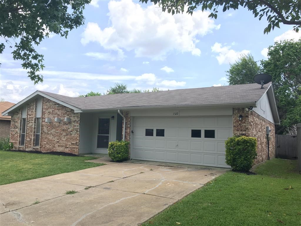 a white and brick house with a driveway and lawn