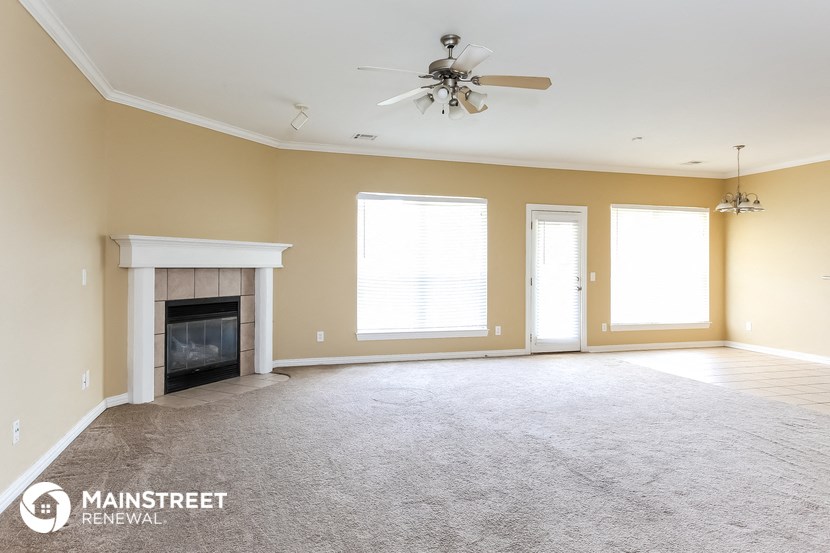 an empty living room with a fireplace and a ceiling fan