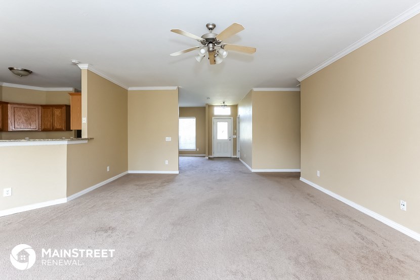 a spacious living room with carpet and a ceiling fan