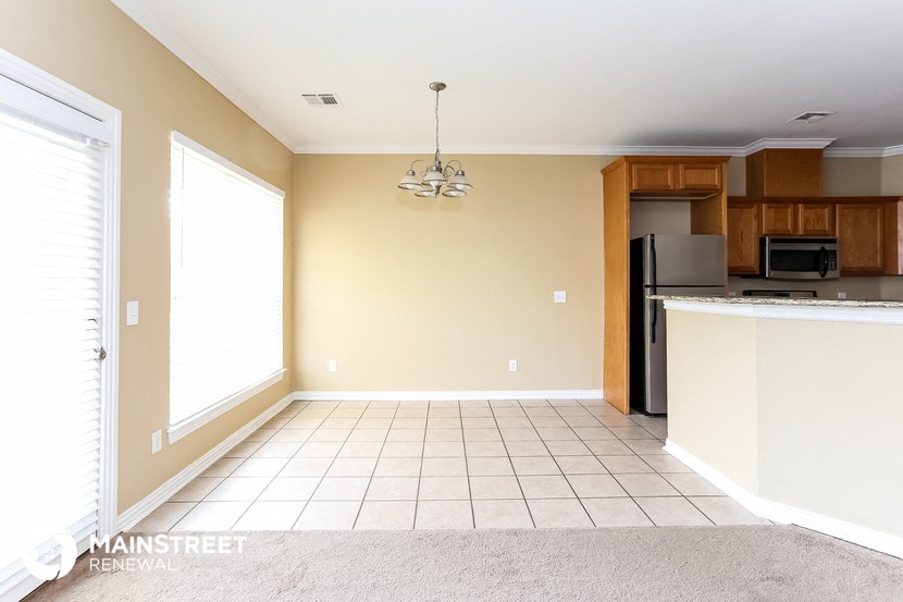an empty dining room with a kitchen with a refrigerator and a sink