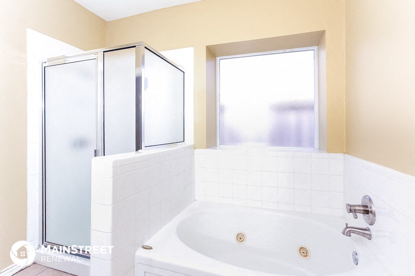 a bathroom with a tub and a shower and a window