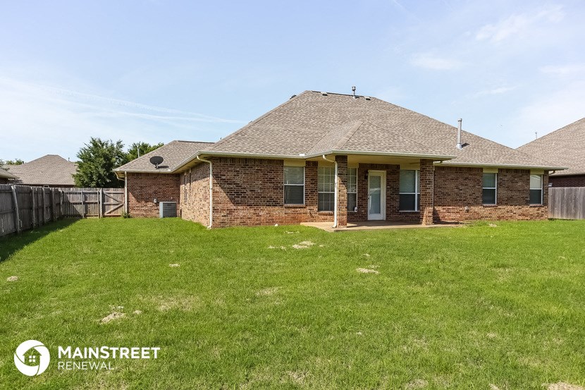 the front of a brick house with a lawn and a fence