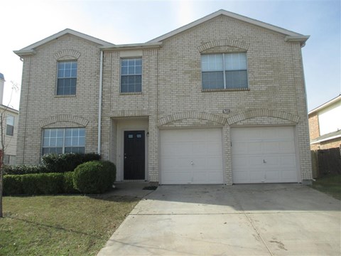 a brick house with two garage doors and a sidewalk