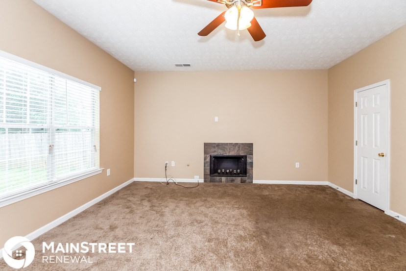 an empty living room with a fireplace and a ceiling fan