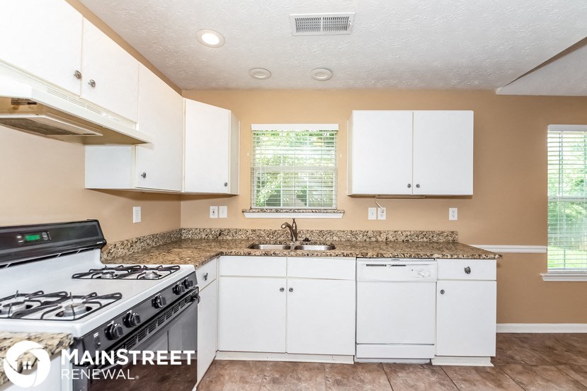 a kitchen with white cabinets and a stove and a sink