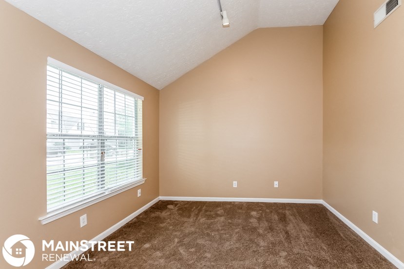 the spacious living room with large window and carpeted flooring