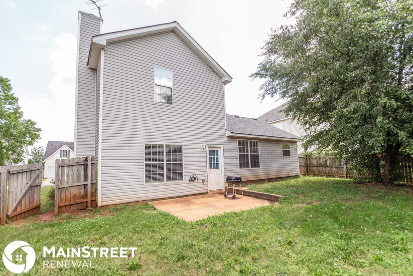 a backyard with a white house and a fenced in yard