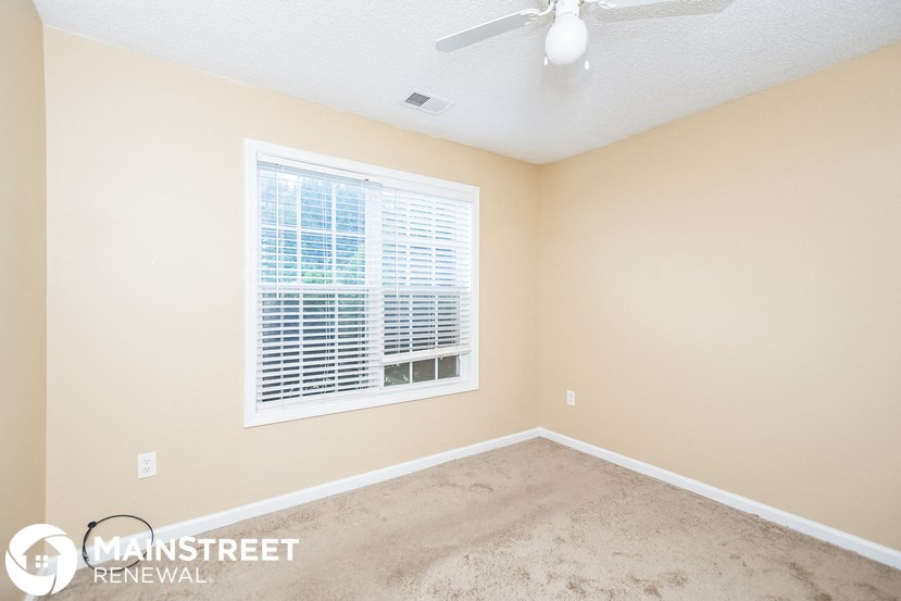 an empty room with a window and a ceiling fan