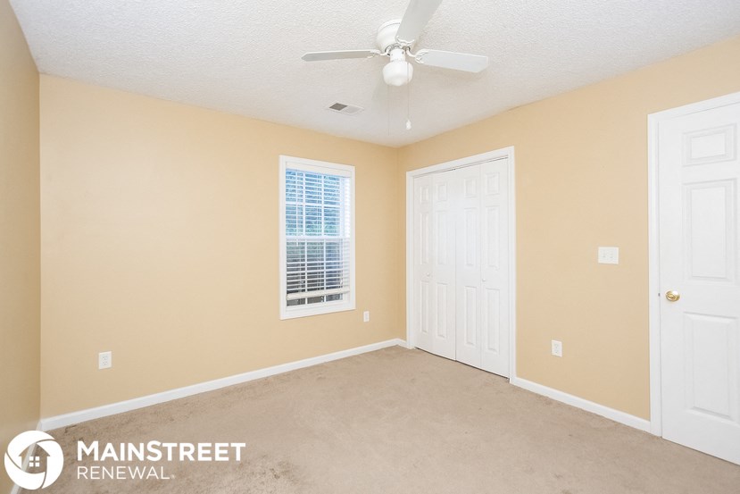 a bedroom with two white doors and a ceiling fan