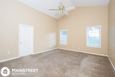 a living room with carpet and a ceiling fan