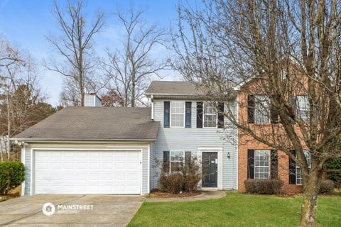 a white house with a white garage door and a red brick house