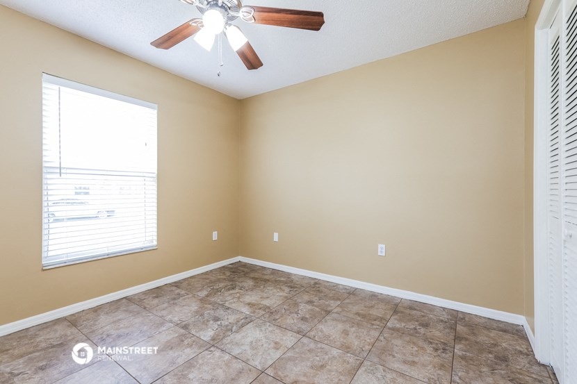 an empty living room with a ceiling fan and a window