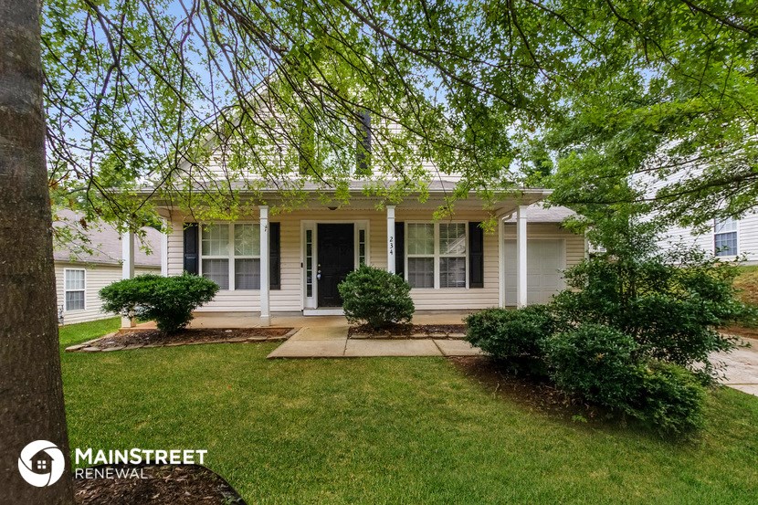 a small white house with a lawn and a tree