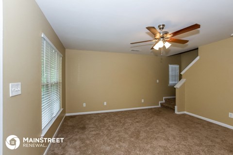 a living room with carpet and a ceiling fan