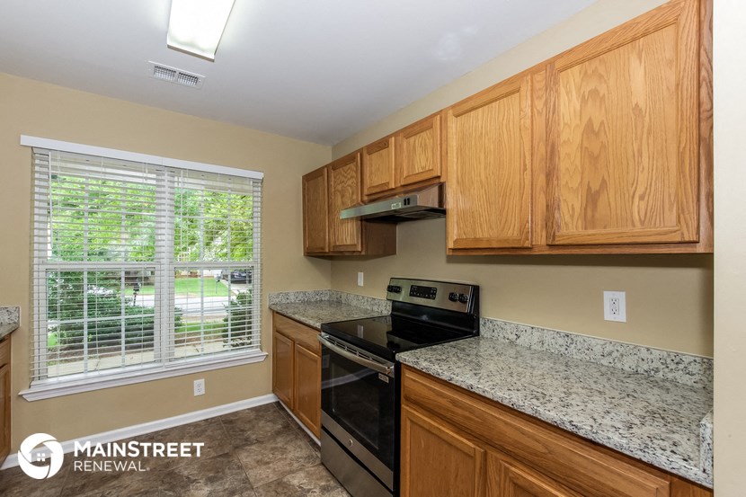 the kitchen has granite counter tops and wood cabinets and black appliances