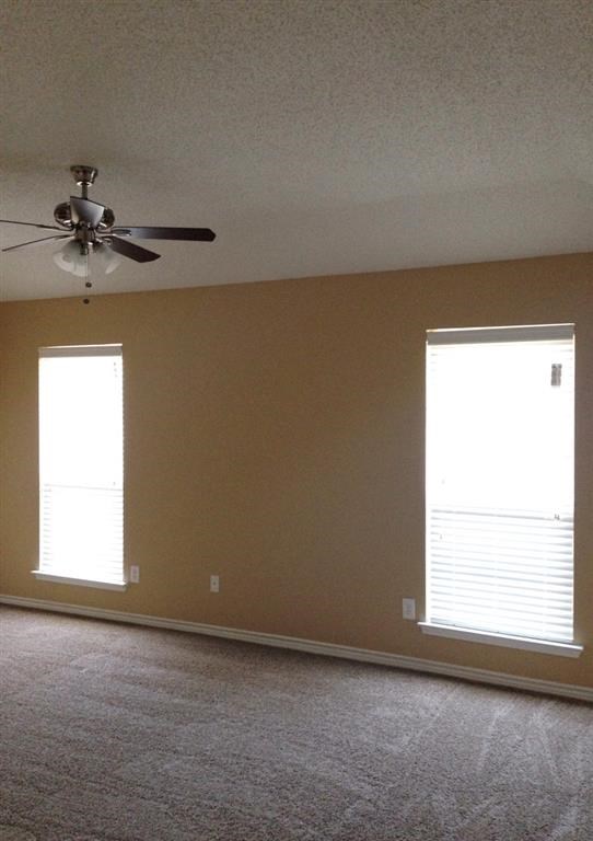 a living room with a ceiling fan and two windows