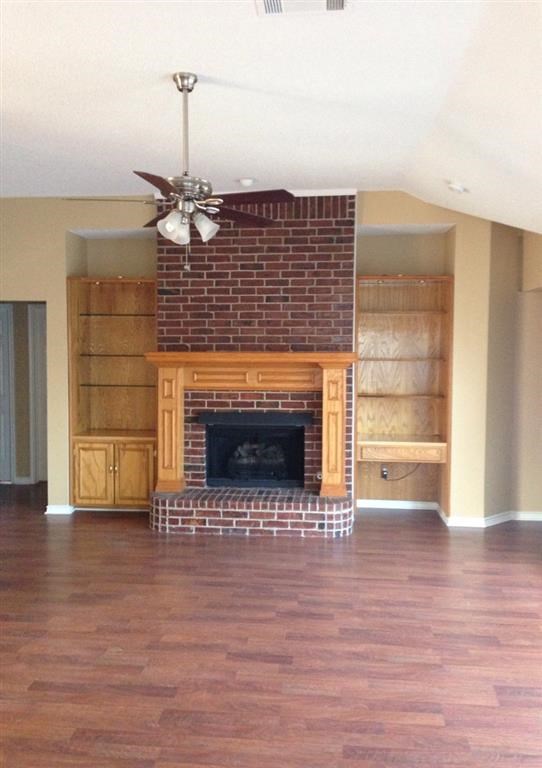 a living room with a brick fireplace and a wooden floor