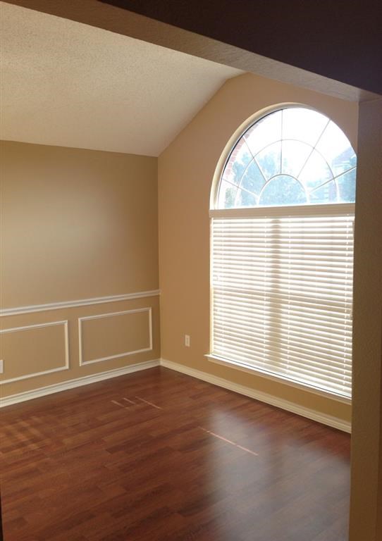 an empty room with a large window and wooden floors
