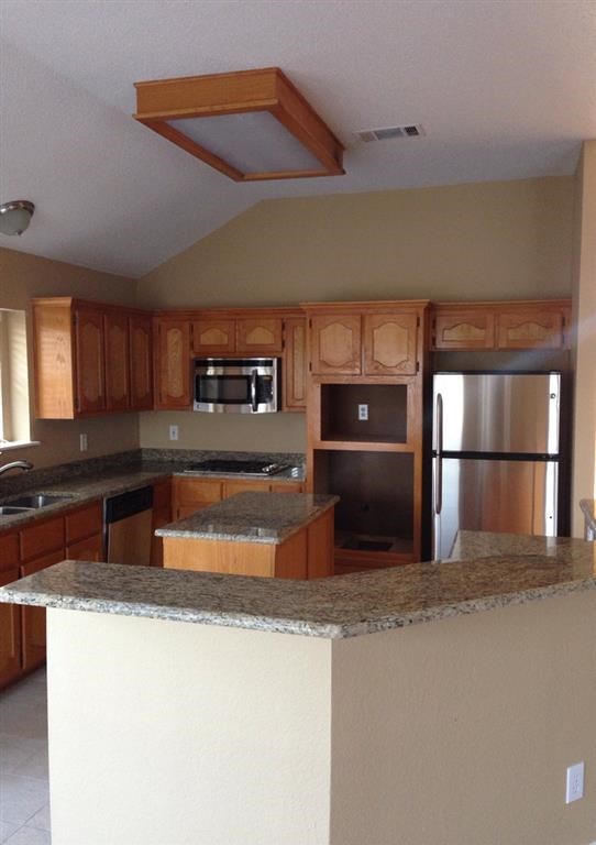 a kitchen with wooden cabinets and stainless steel appliances