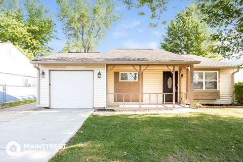 a small yellow house with a porch and a white garage