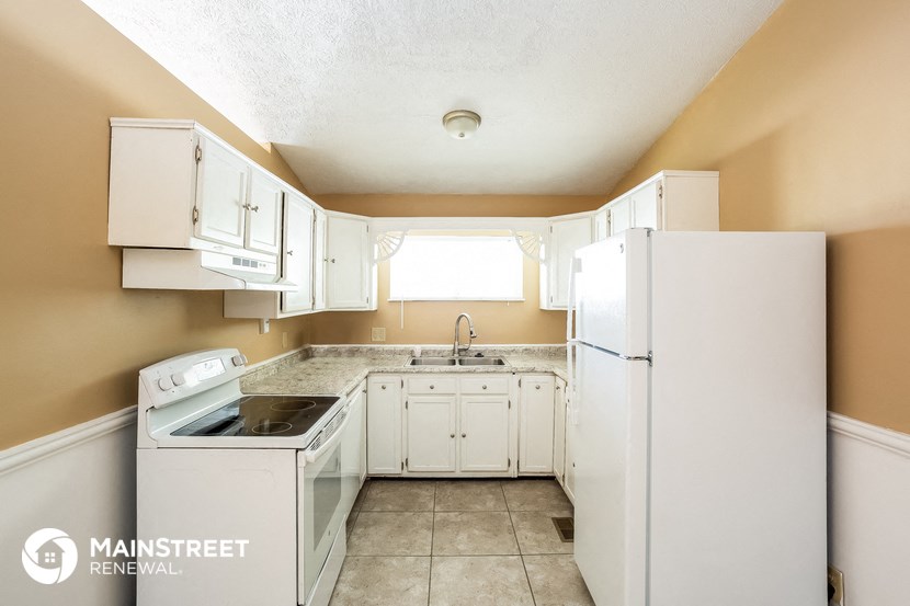 a kitchen with white cabinets and a sink and a refrigerator
