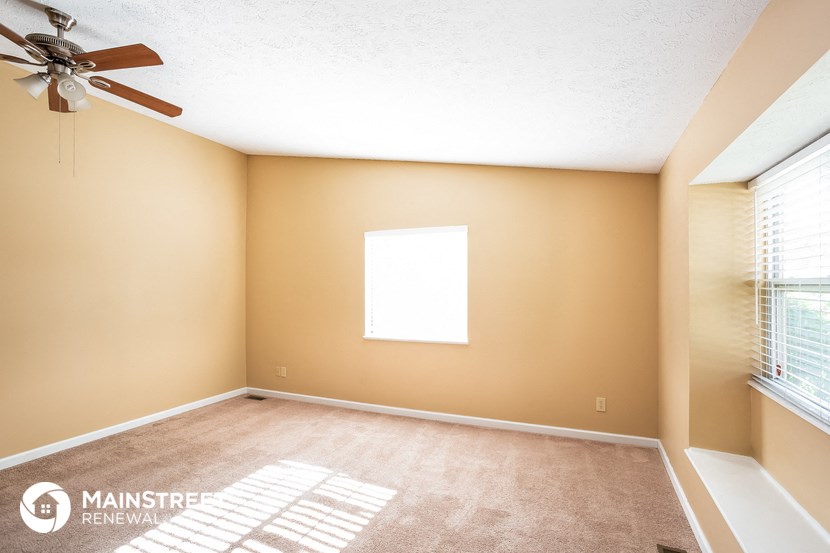an empty room with a ceiling fan and a window