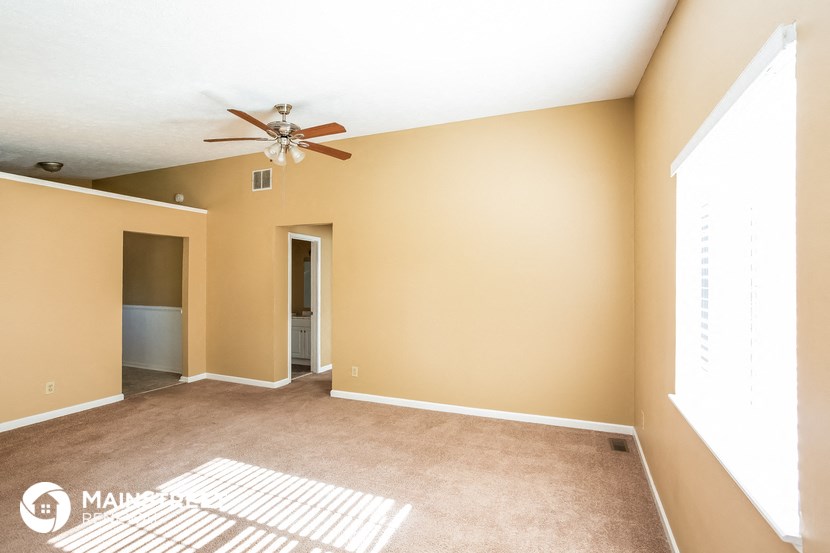 an empty living room with a ceiling fan and a door to a closet