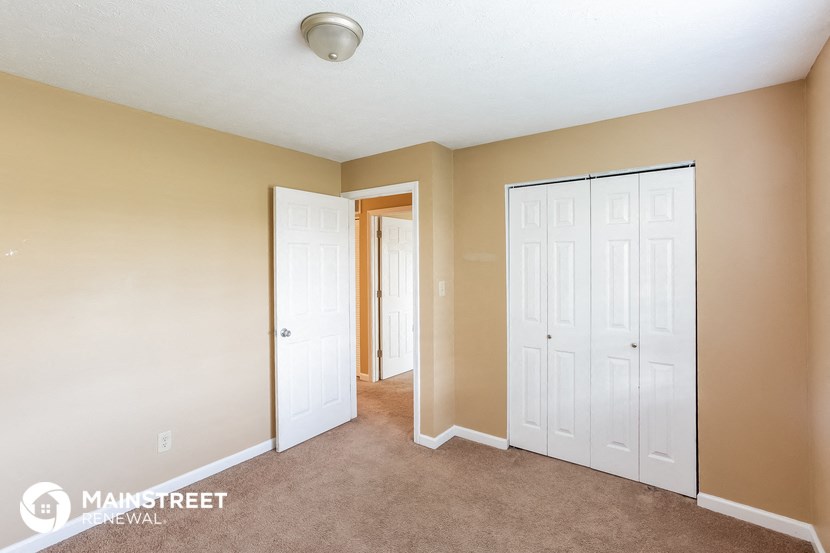 a bedroom with two closets and a carpeted floor and a door to a