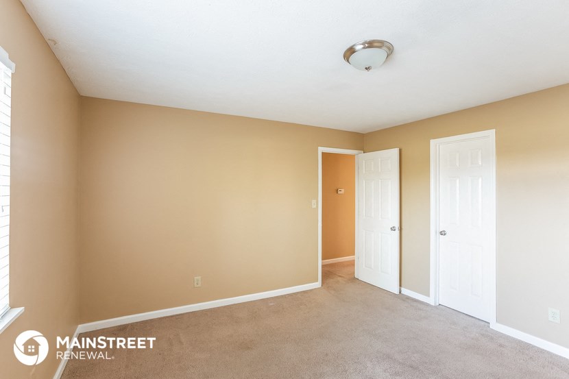 a living room with two doors and a carpeted floor