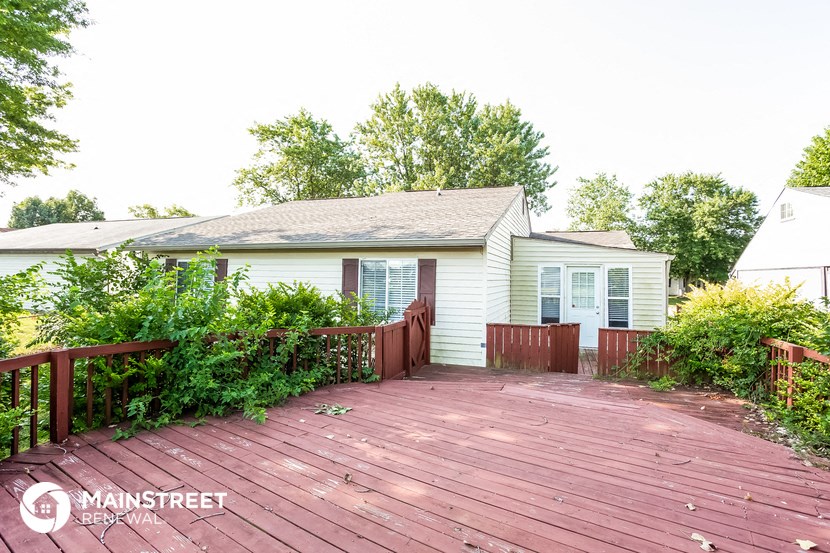 a small white house with a wooden deck