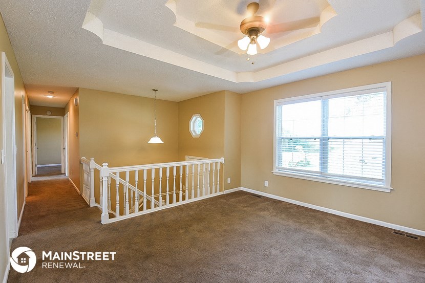 an empty living room with a ceiling fan and a window