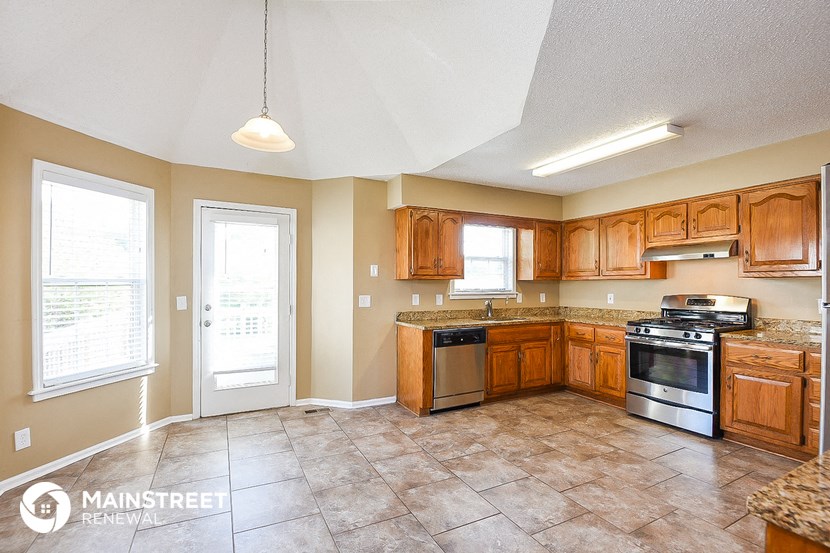 a kitchen with wooden cabinets and appliances and tile floor