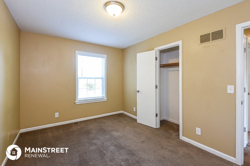 an empty room with a door to a closet and a window