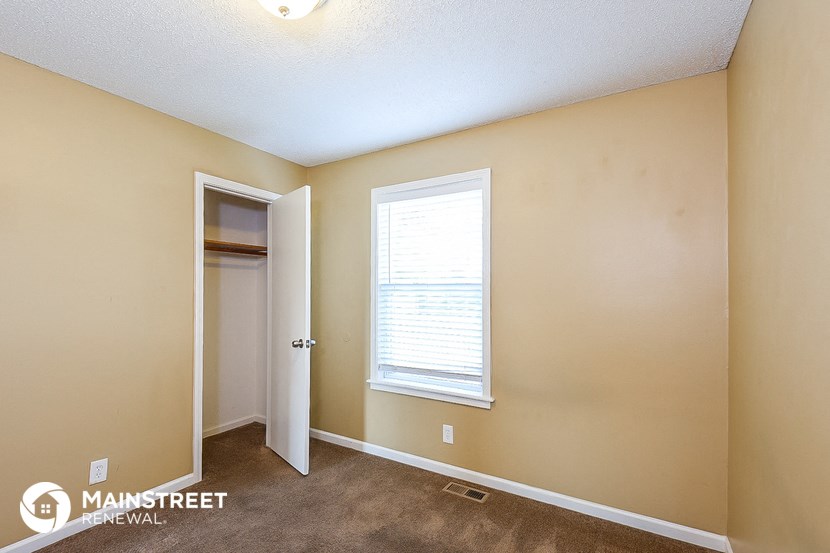 a bedroom with a door to a closet and a window