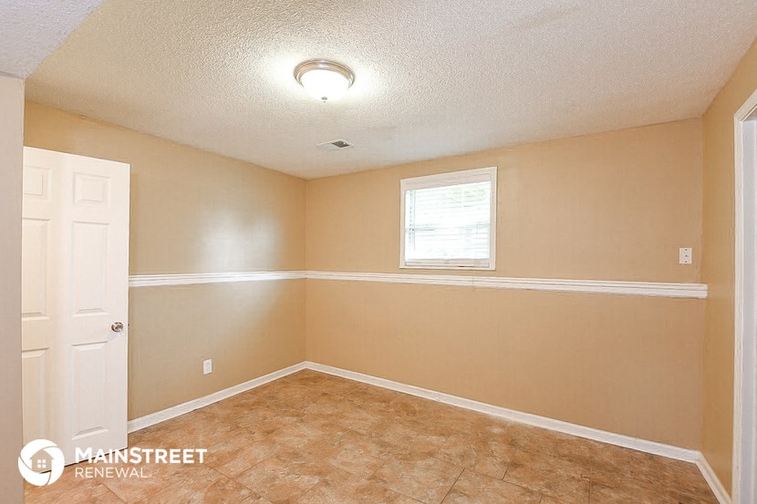 the living room of an empty home with a white door and a window