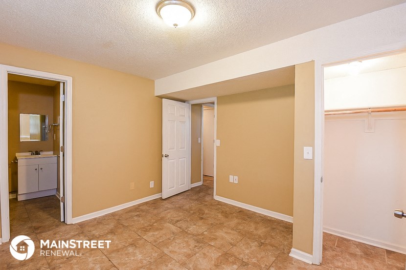 a living room with a door to a bathroom and a closet
