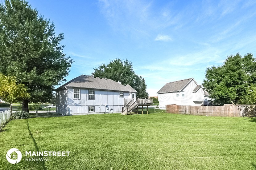 a backyard with a white house and a fence