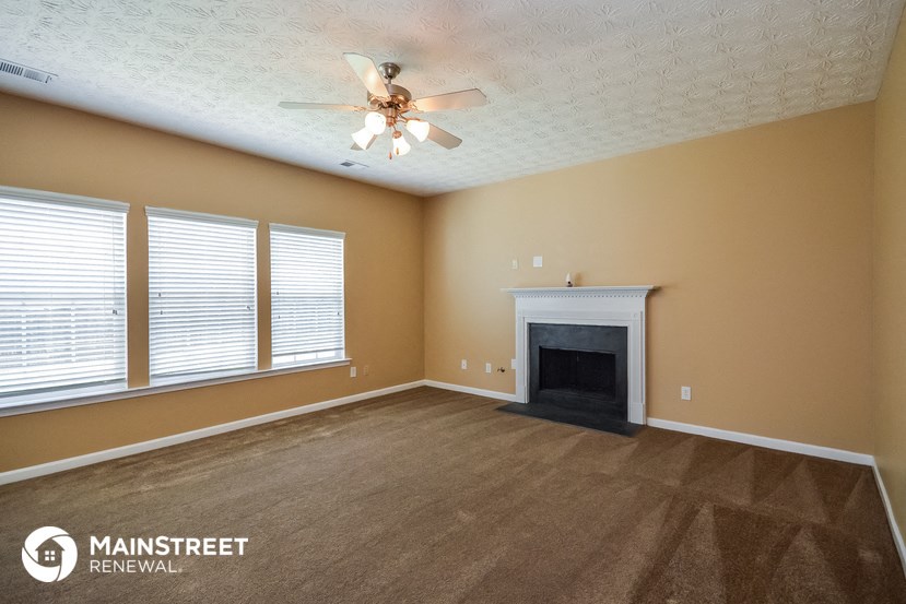a living room with a fireplace and a ceiling fan