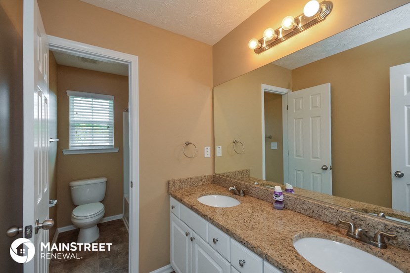 a bathroom with two sinks and a toilet and a mirror