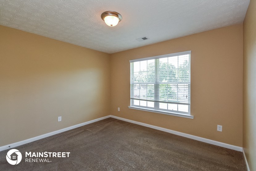 an empty living room with a large window and carpet