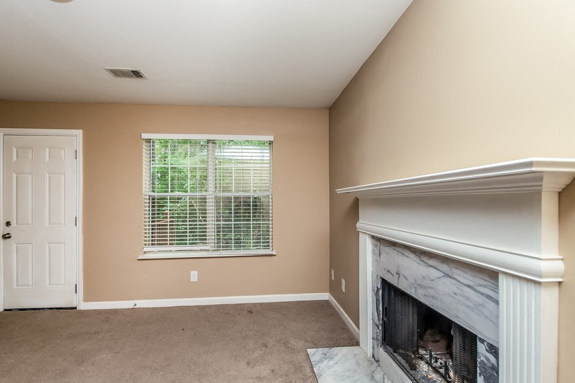 an empty living room with a fireplace and a window