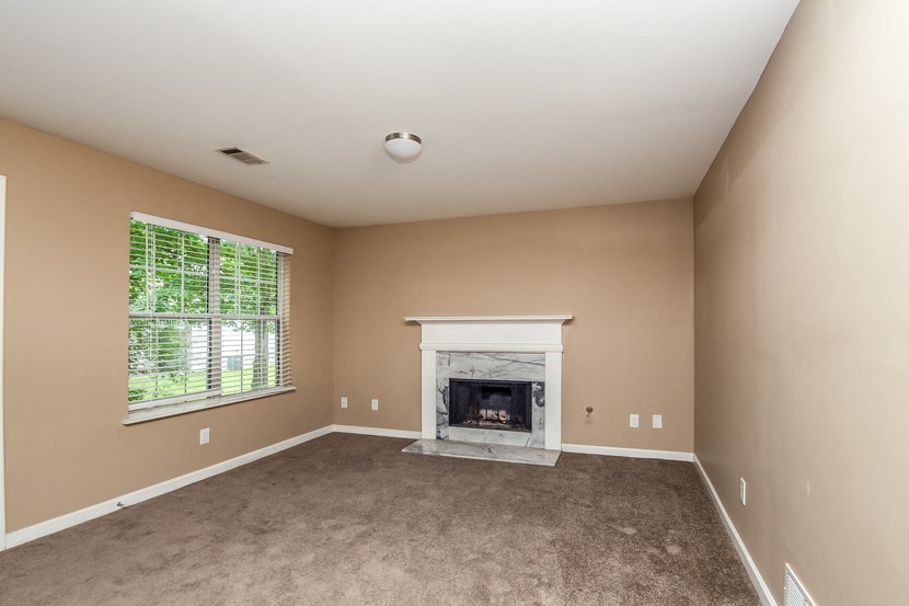 an empty living room with a fireplace and a window